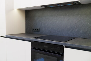 Modern kitchen with sleek appliances and minimalistic design featuring an oven and cooktop