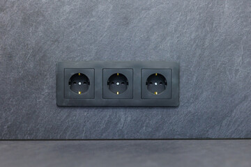 Three electrical outlets installed in a modern kitchen with a sleek stone countertop