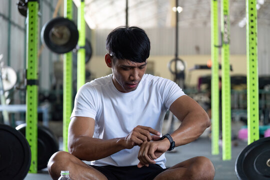 Fitness Tracking and Training. Man checking smartwatch during workout in gym.