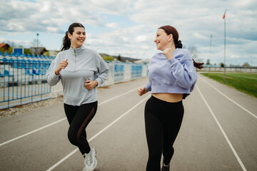Two female friends running or jogging on stadium doing sport activities	
