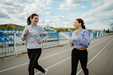 Two female friends running or jogging on stadium doing sport activities	
