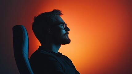 A man with glasses sits in profile against an orange-red gradient background, creating a dramatic and thoughtful mood.
