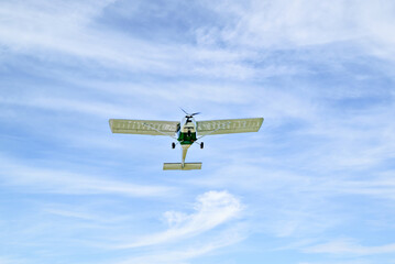 Single engine ultralight plane flying in the blue sky with white clouds	