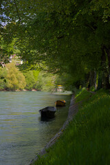 Two simple boats rest quietly on serene waters, reflecting tranquil moments by a green-banked...