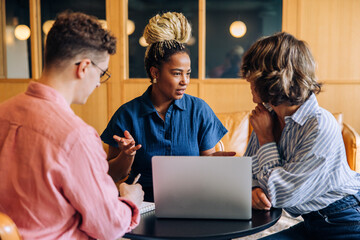 Three young adults having a business discussion in a modern coworking office space