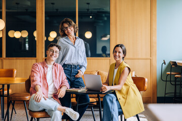 Plakat Three colleagues in a casual setting discussing ideas and working on a laptop