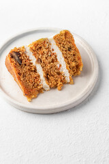 Homemade layered carrot cake with cream cheese, walnuts and spices on a plate isolated with text space