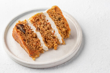 Homemade layered carrot cake with cream cheese, walnuts and spices on a plate isolated with text space