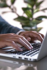 Close-up of hands typing on laptop keyboard in bright workspace. Remote work theme.