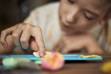 Child with disability focusing on crafting with colorful materials, bringing creative ideas to...