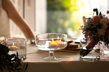 Floating candles illuminating wedding reception table setting with bridal bouquet