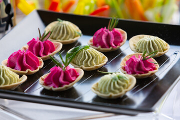 Colorful canapés with beetroot and herb cream cheese garnishing a serving tray