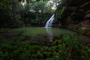 Obraz premium Waterfall surrounded by lush green environments.