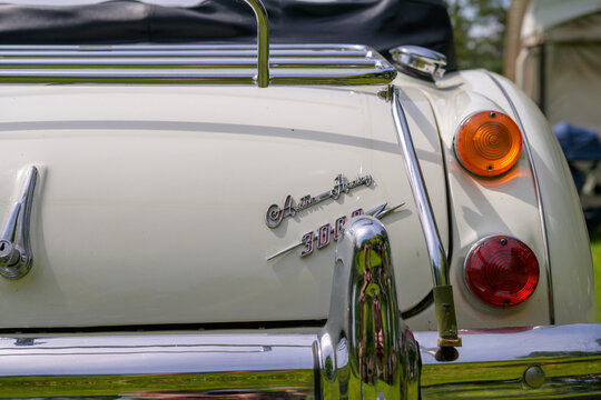 Vintage Austin Healey Tailgate: A classic cream-colored convertible with chrome accents and distinctive tail lights on display.