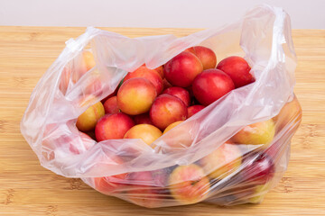 Fresh red plums in a transparent plastic bag