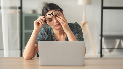Young woman suffers from eye pain and rubs her eye