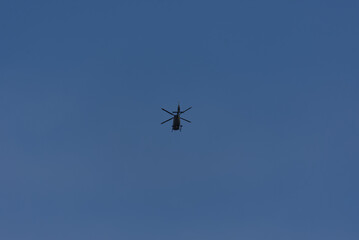 A lone helicopter soars through a vast, clear blue sky, a powerful silhouette against the open expanse. Evokes feelings of freedom and aerial dominance.