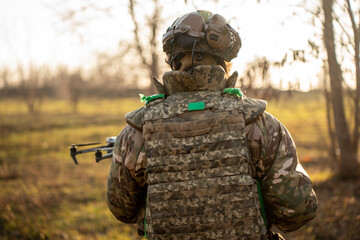 ukrainian soldier in camouflage is raising a small drone , preparing for takeoff in a forested...