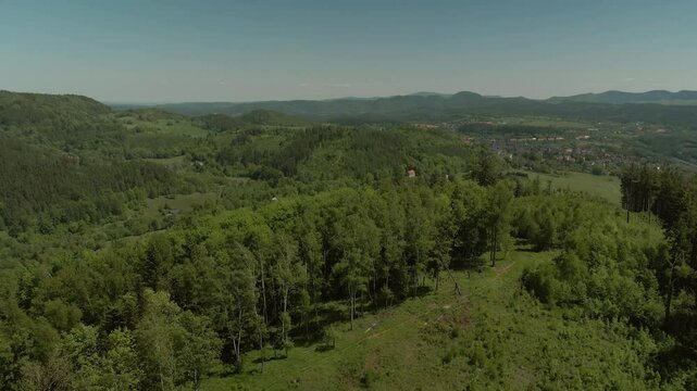 Aerial view of hilly forest landscape leading to a distant town nestled among valleys and mountains in Bogusz&oacute;w-Gorce in the Chełmiec mountain region