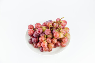A bunch of fresh grapes and fruits on a white plate