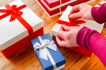 Birthday gifts. Person Wrapping Gifts with Decorative Ribbons. Festively Wrapped Gift Boxes on...
