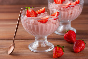 Tofu and strawberry mousse dessert in a glasses with spoon on a brown table. Vegan food. Lactose and sugar free.