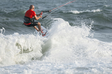 Extreme kitesurfer riding a kite on the waves in the sea