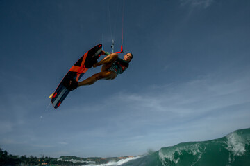 young brunette woman in sports swimsuit extreme kite riding in the sea on the waves
