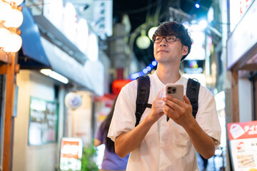 スマホを持って街を歩く男性