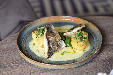 Sea Bream Fillet with Béarnaise Sauce, Herbs, and Potatoes Served on Wooden Table