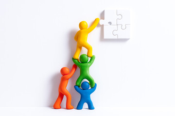Colorful human figures working together to assemble puzzle piece symbolize teamwork and collaboration in achieving common goal