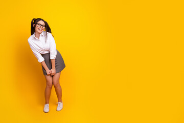 Playful young woman in casual outfit posing on vibrant yellow background with cheerful and youthful energy visible