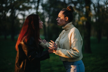 A tense interaction between two women in outdoor natural surroundings during sunset. They appear to...