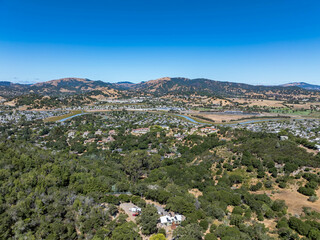 Aerial photos of a forested hillside in San Rafael, California, highlighting dense tree coverage, winding roads, and panoramic views of surrounding hills, residential properties, and the San Pablo Bay