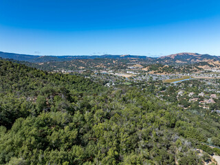 Aerial photos of a forested hillside in San Rafael, California, highlighting dense tree coverage, winding roads, and panoramic views of surrounding hills, residential properties, and the San Pablo Bay