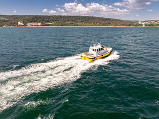 Pilot boat crashing through waves, going to a cargo ship.