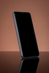 Modern Smartphone with Blank Black Screen for Mockup, Sleek Design, Reflecting on Glossy Surface. Tech Concept on Brown Background.
