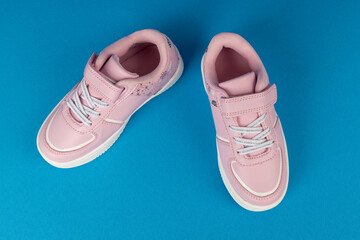 Cute Pink Kids' Fashion Sneakers: Stylish Children's Shoes with Velcro Strap on Blue Background. New Footwear Concept