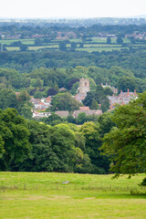 Obraz premium Our green and pleasant land, landscape view over forests towards a village with a church at its centre in rural England on a summers day, nature and space surrounding a lovely place to live.