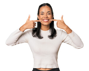 Young Filipina woman smiles, pointing fingers at mouth.