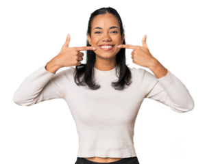 Young Filipina woman smiles, pointing fingers at mouth.