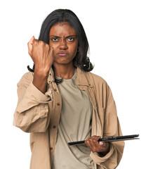 Young Indian woman with digital tablet showing fist to camera, aggressive facial expression.