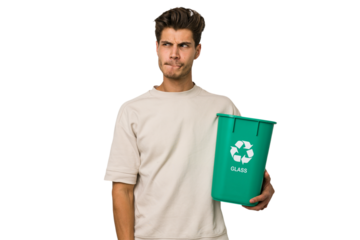 Young caucasian man holding a glass trash isolated confused, feels doubtful and unsure.