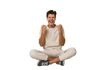 Young caucasian man sitting on the floor isolated on white background cheering carefree and excited. Victory concept.