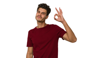 Young handsome caucasian man isolated on white background winks an eye and holds an okay gesture with hand.