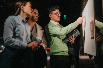 Group of people discussing and observing an exhibit in a museum setting. They appear engaged and...