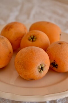 A rustic still life featuring loquat fruits on a wooden table, evoking a sense of Mediterranean charm