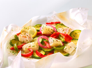 Kabeljaufilet mit Zucchini und Paprika mit Zwiebeln in Papier, Fisch, isoliert, gemüse, gedämpft,