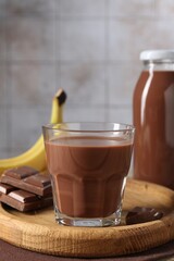 Tasty chocolate milk, pieces and banana on table, closeup
