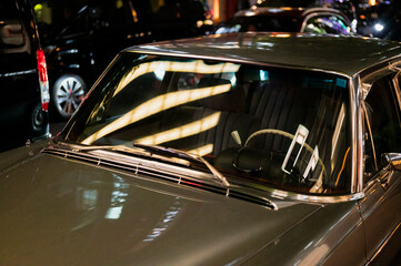 Reflection on windshield of classic car parked at night